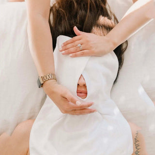 Person wearing a white dress with a cutout design, holding their hands together.