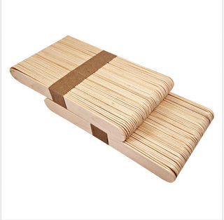 Pack of wooden popsicle sticks with a brown band on a white background. Waxness Body Waxing sold by Xrosebeauty